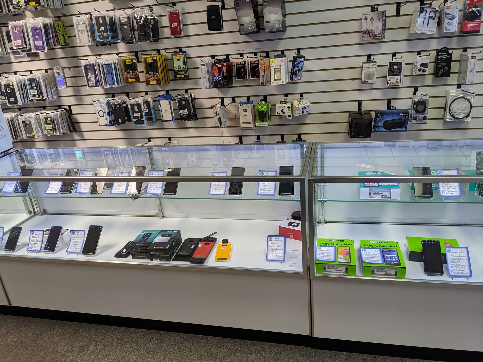 A cellphone store display with phones in glass cases and accessories on the wall.