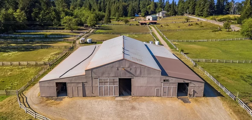 An aerial view of a large barn in the middle of a grassy field.