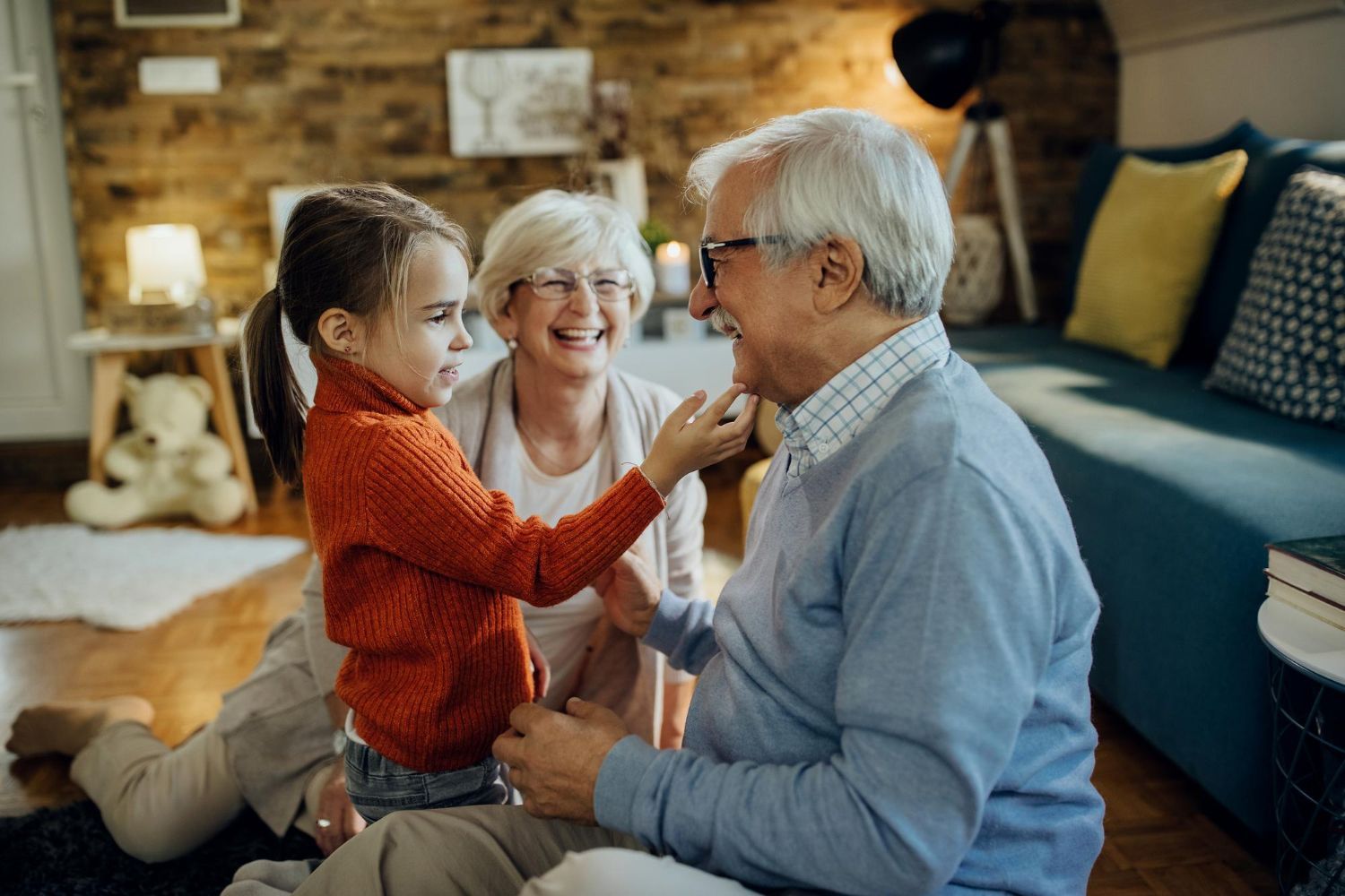 Child touching an older man’s face while a smiling woman watches in a cozy living room