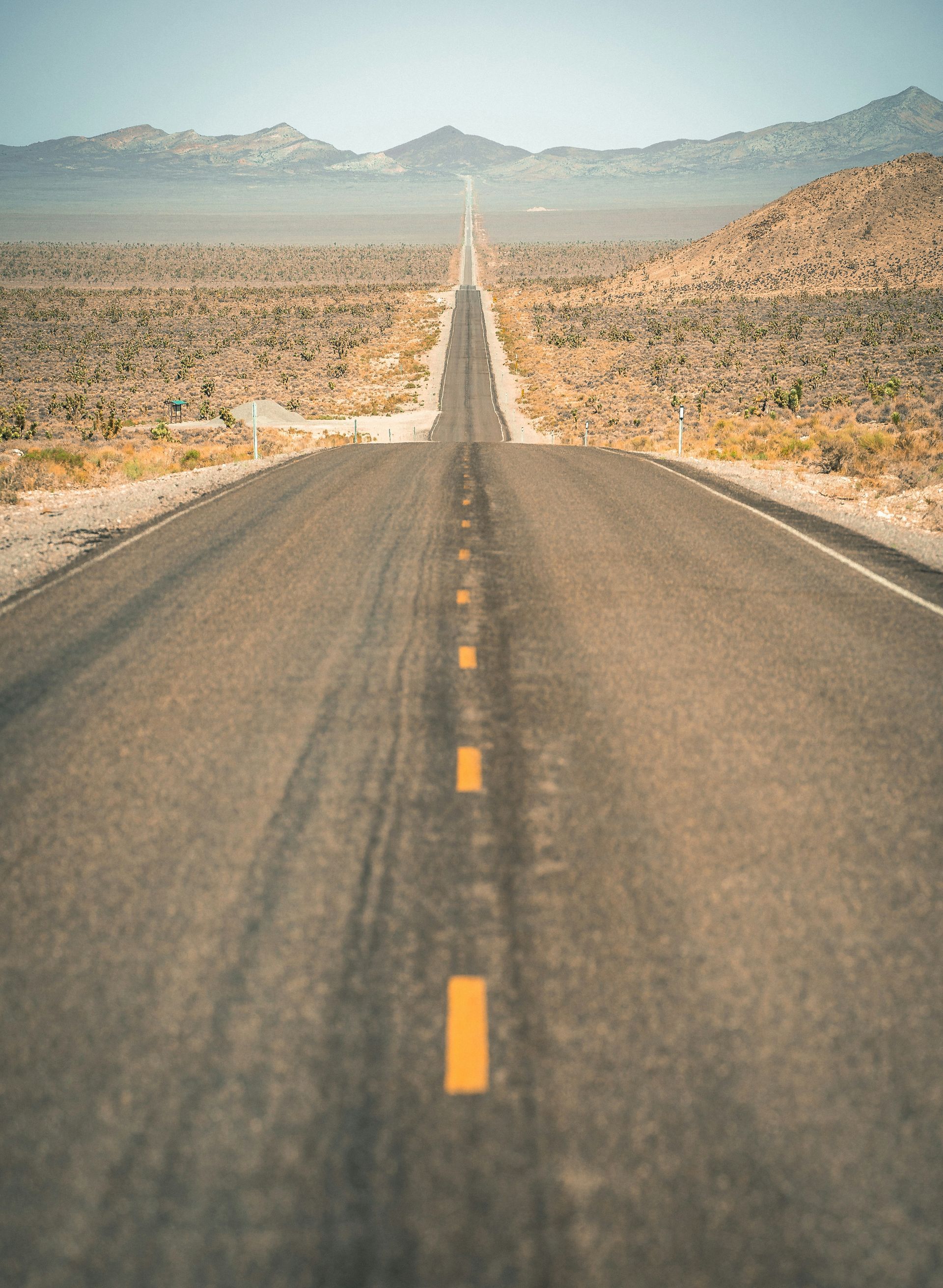 Long straight desert highway stretching toward distant mountains under a clear sky