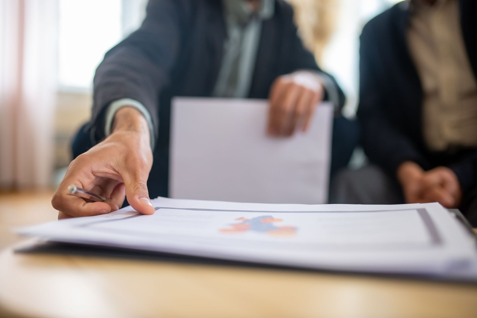 Business meeting with a hand pointing at documents on a table