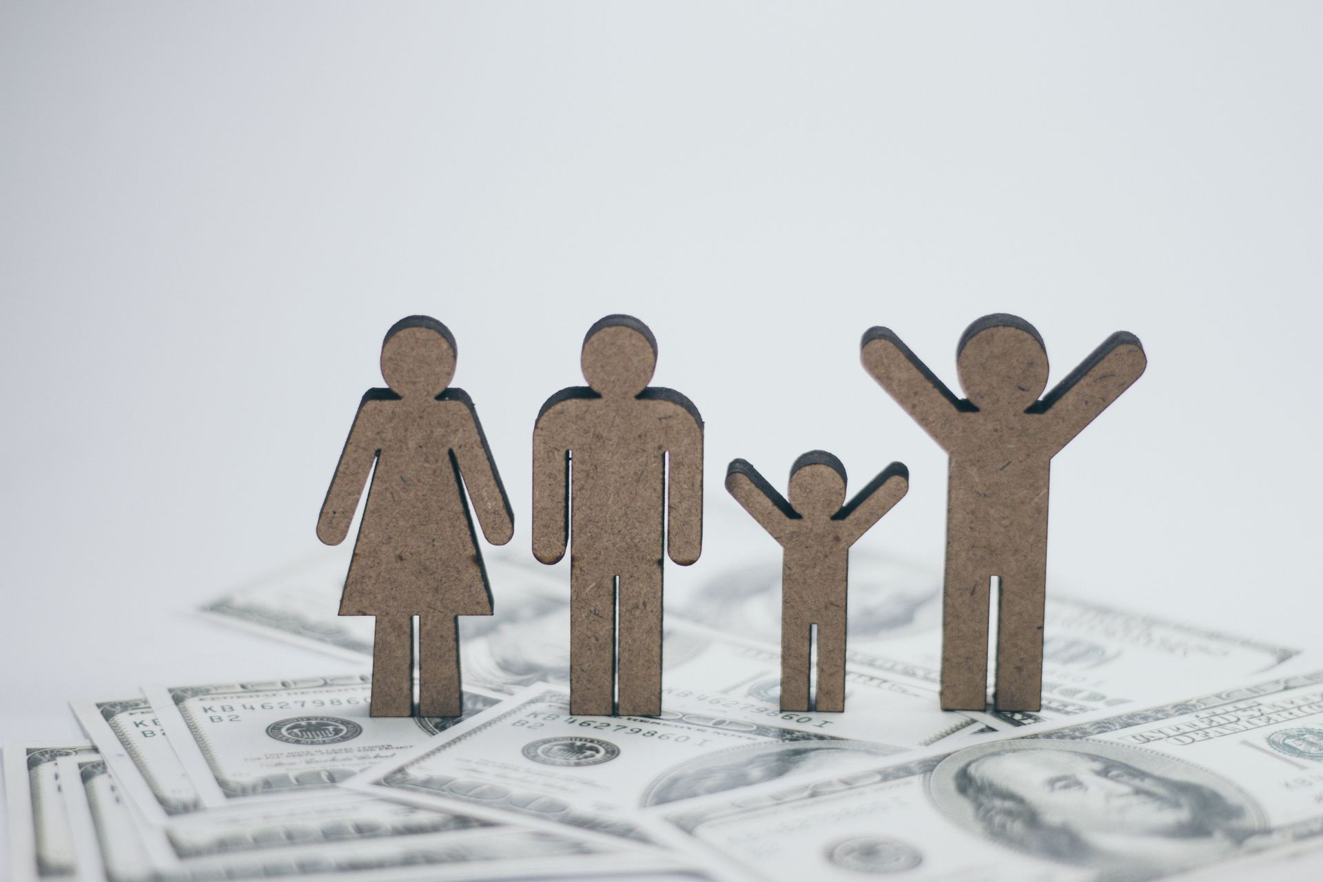 Paper family figures standing on scattered U.S. dollar bills, symbolizing finances or family budgeting.