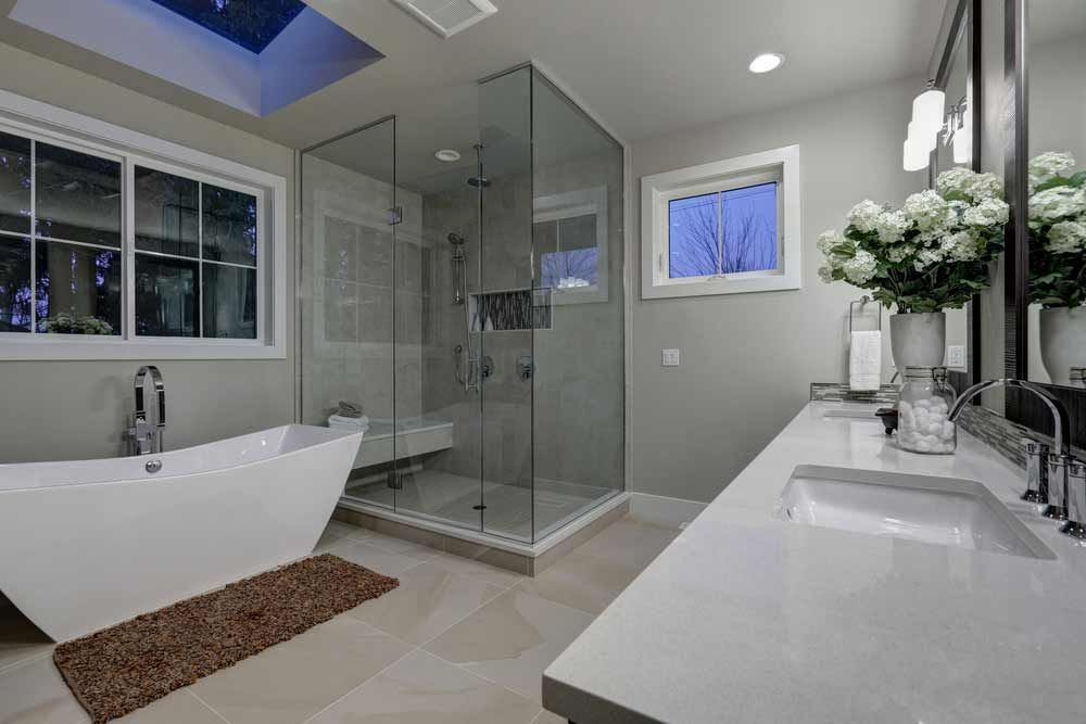 Modern bathroom with a bathtub, glass shower, and double vanity.