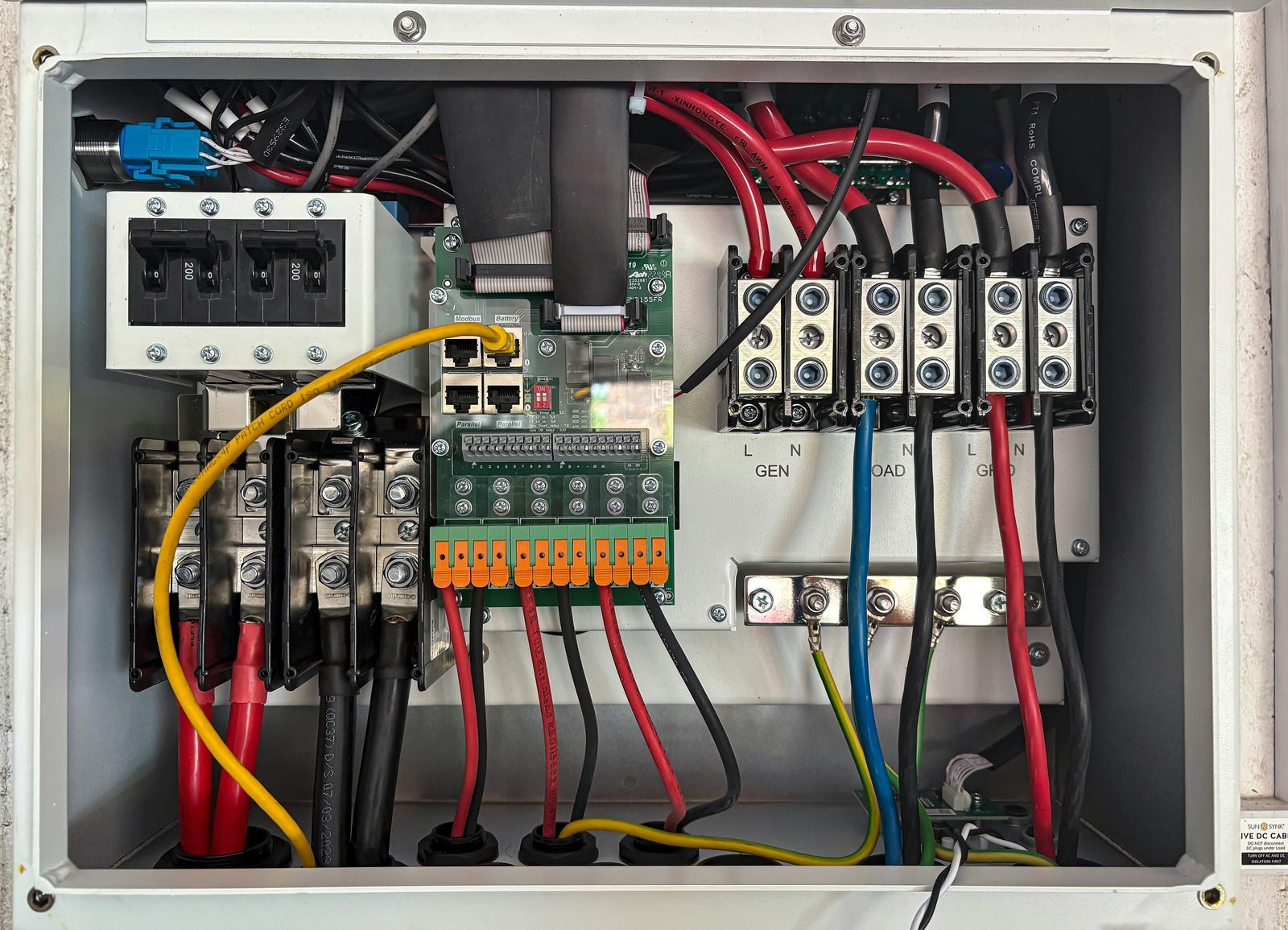 Open electrical control panel with circuit breakers, relays, terminal blocks, and wiring.