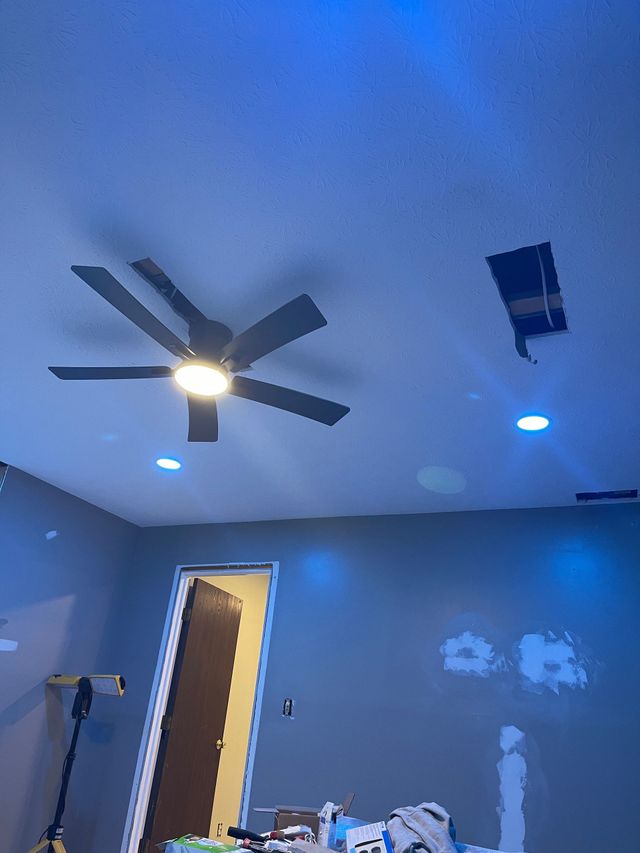 Blue-painted room with ceiling fan, recessed lights, open door, and a ladder against the wall.