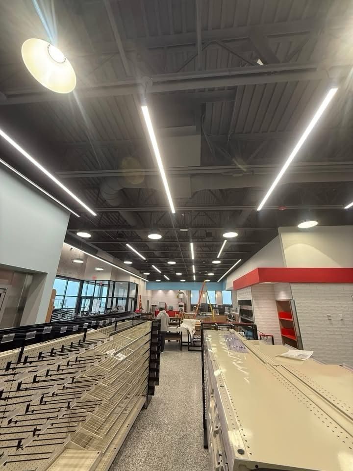 Wide store interior with rows of shopping carts and bright ceiling lights above checkout lanes
