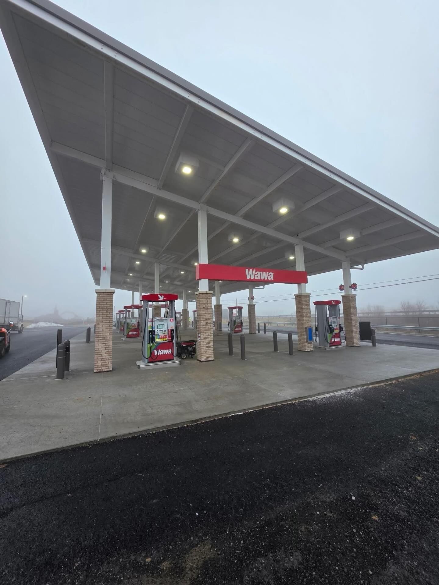 Empty gas station canopy with a red sign on a foggy roadside at dawn