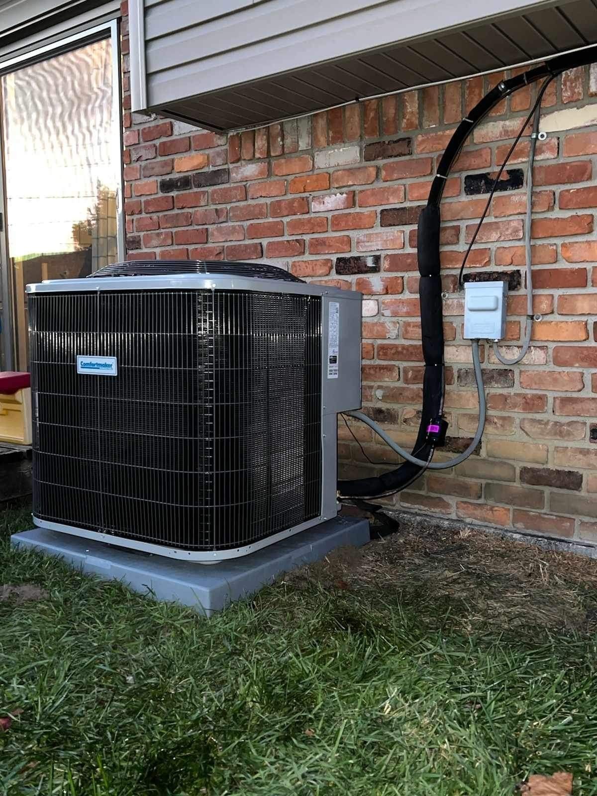 An air conditioner is attached to the side of a brick building