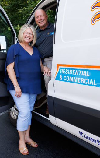 Woman and man stand by a van; the van reads