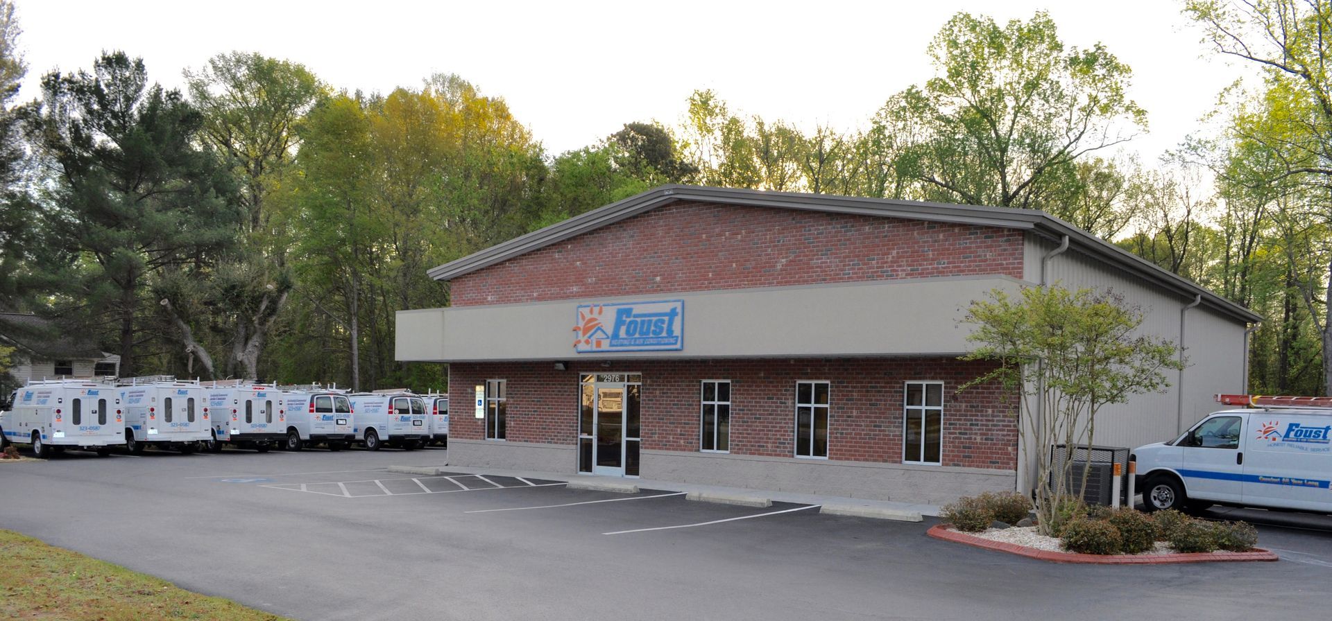 Building with sign, parked vans, trees.