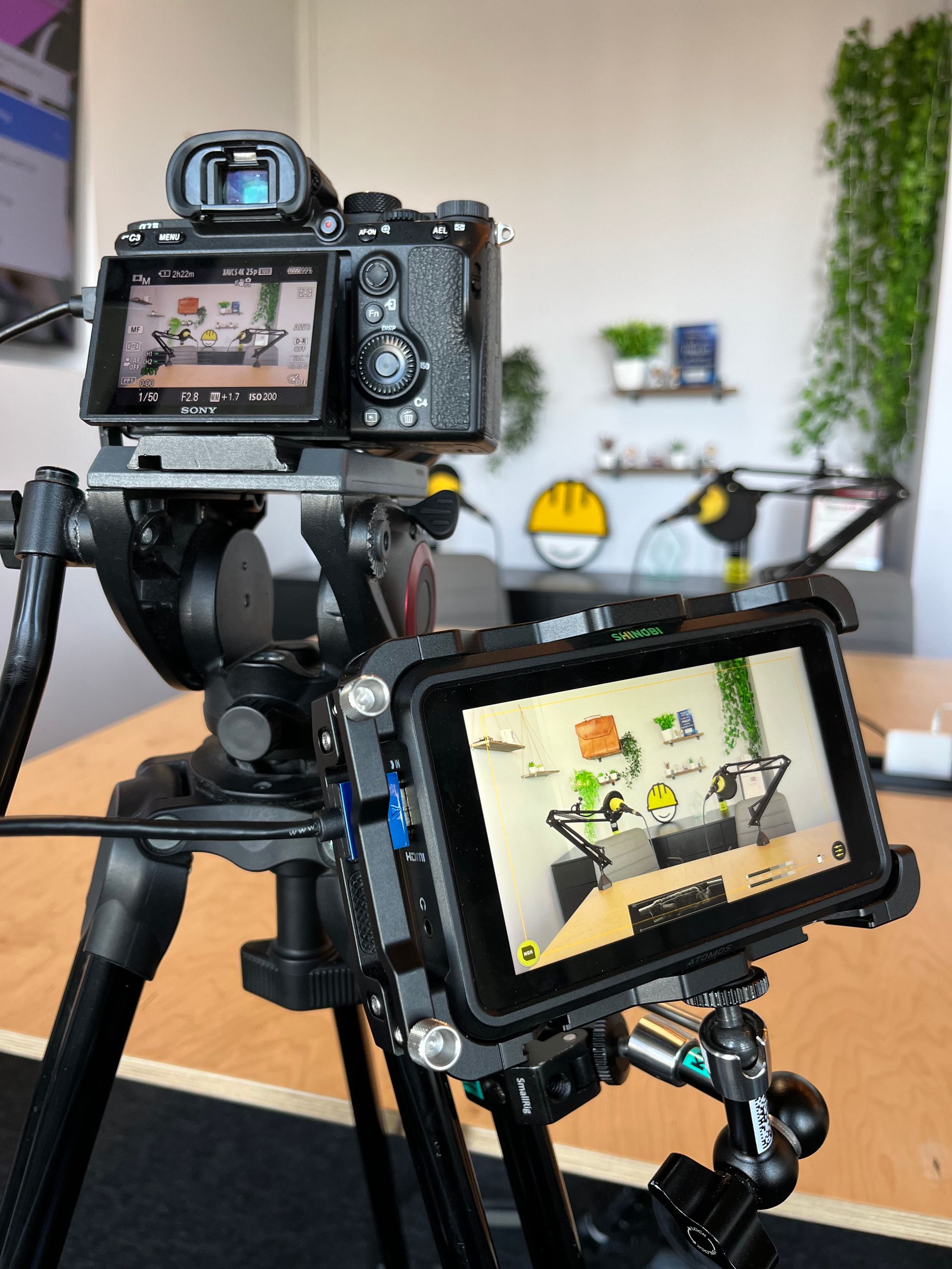 Camera setup on a tripod, including a camera and an external monitor, capturing a podcast recording.