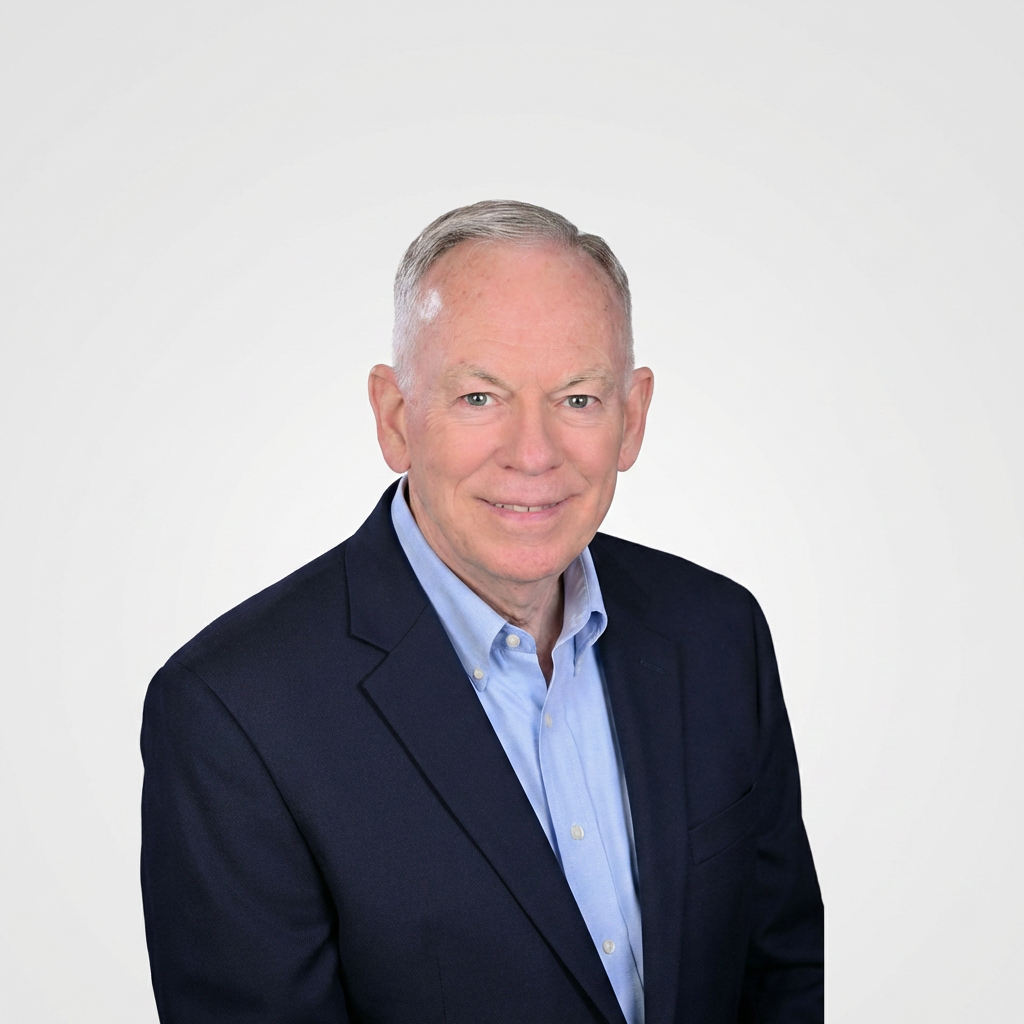 Professional headshot of a smiling man in a navy blazer and light blue shirt on a white background