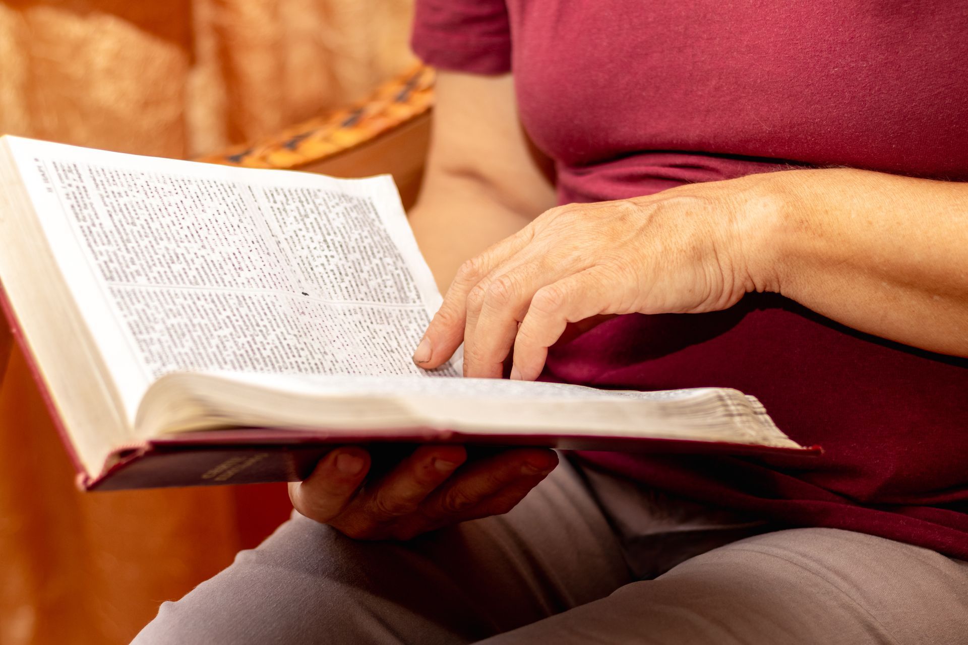 Person holding an open book and reading on a couch