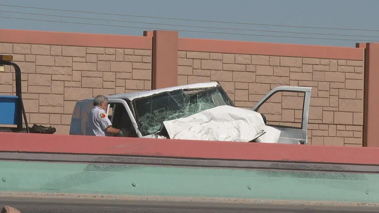 A man is sitting in the back of a truck with a broken windshield.