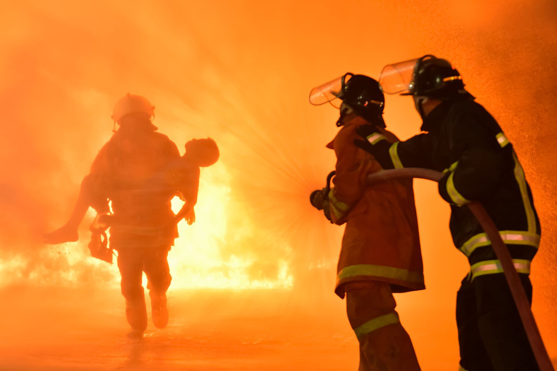 Two firefighters are fighting a fire with a hose
