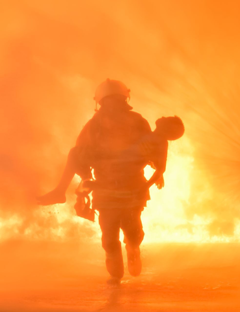 A fireman is carrying a person through a fire