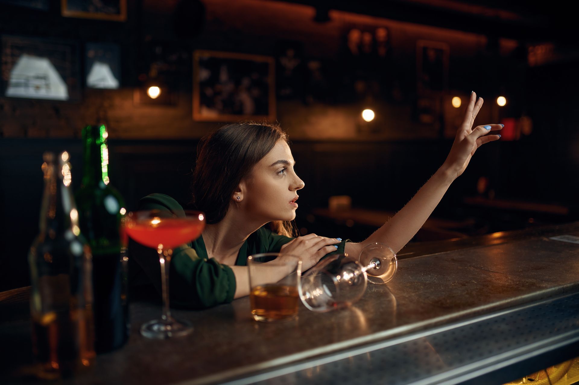 A woman is sitting at a bar holding a glass of wine.