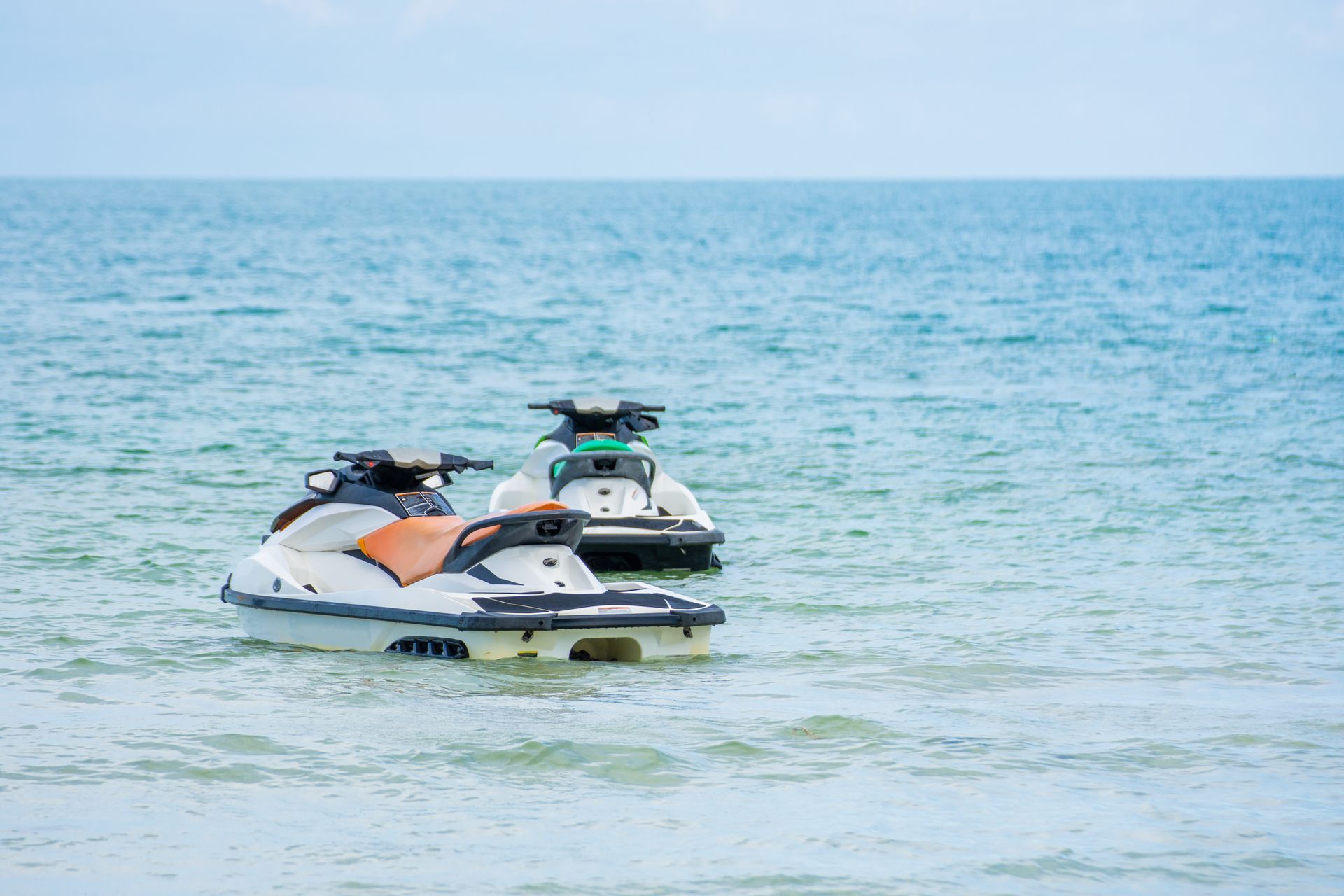 Two jet skis are floating on top of a body of water.