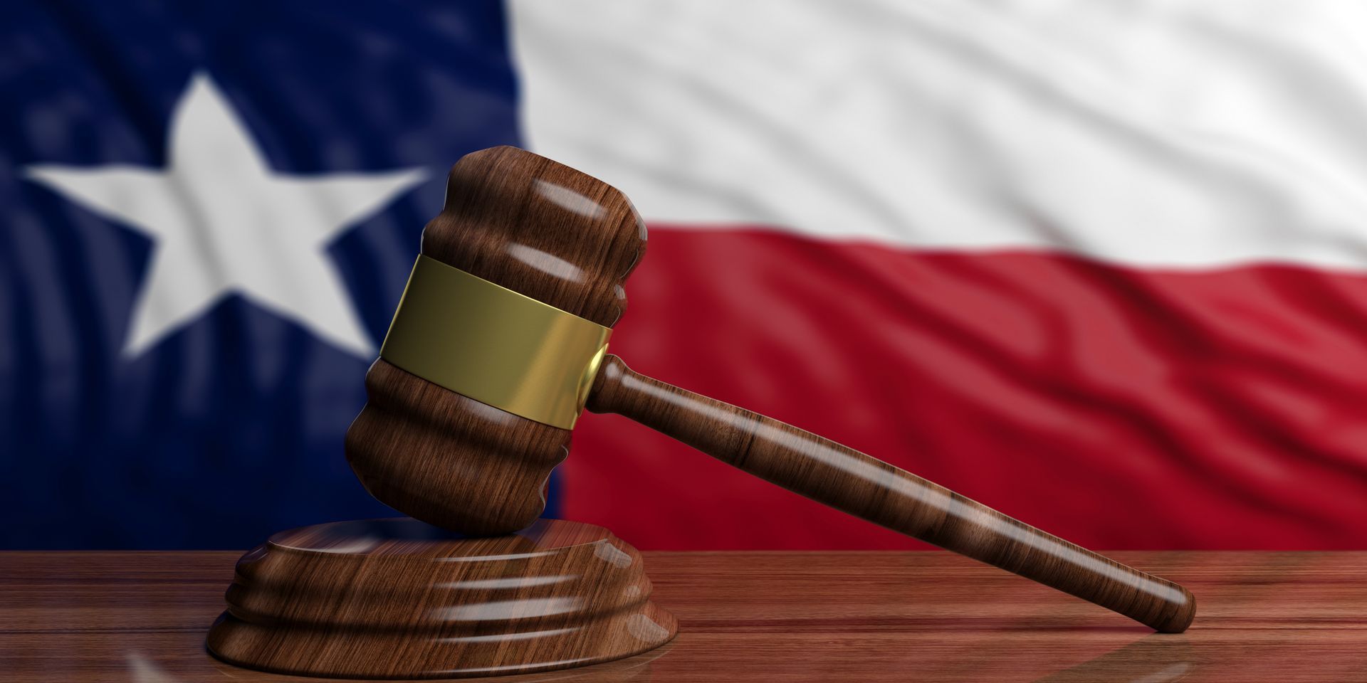 A wooden judge 's gavel is sitting on a wooden table in front of a texas flag.