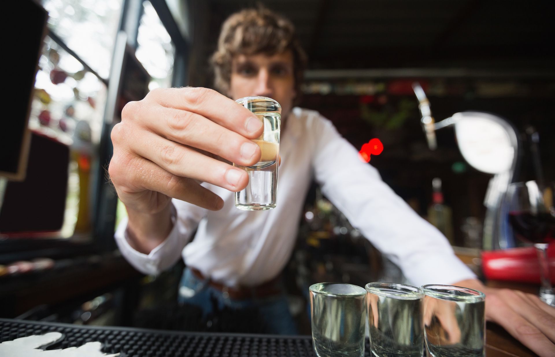 A man is taking a shot of tequila at a bar.
