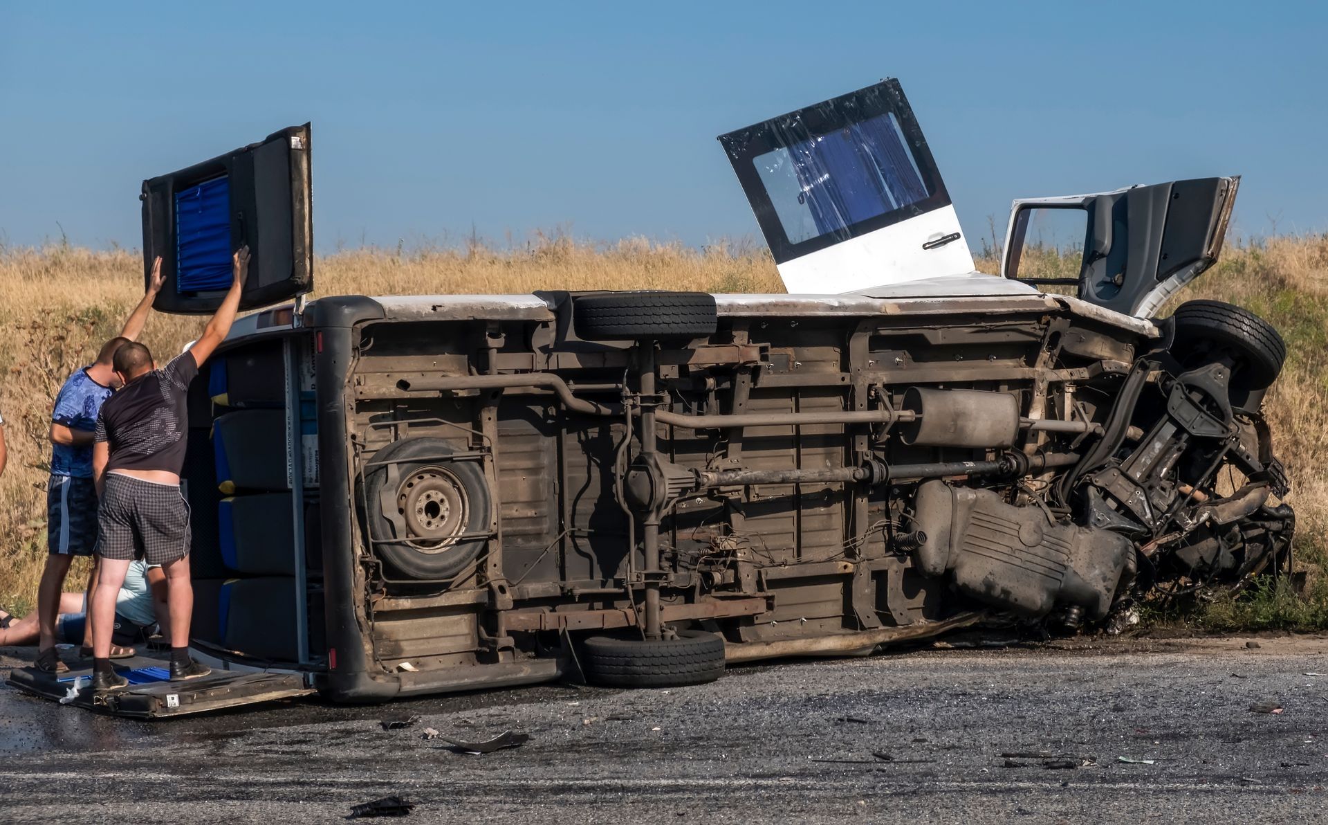 A truck has turned over on its side on the side of the road.