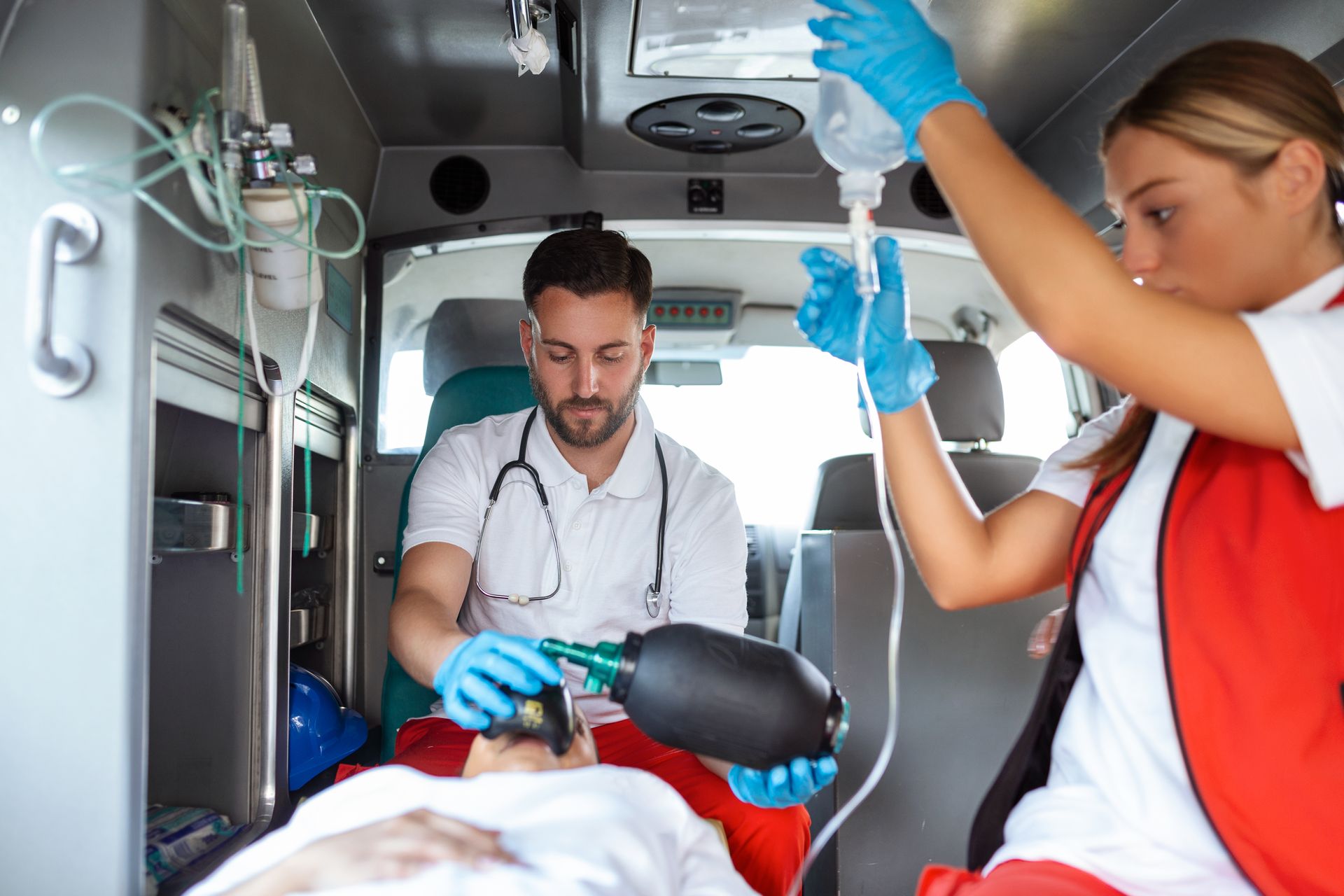 A man and a woman are giving a patient an oxygen mask in an ambulance.