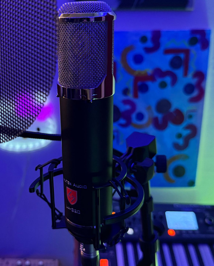 Studio microphone on a stand with purple-blue lighting and a patterned panel in the background