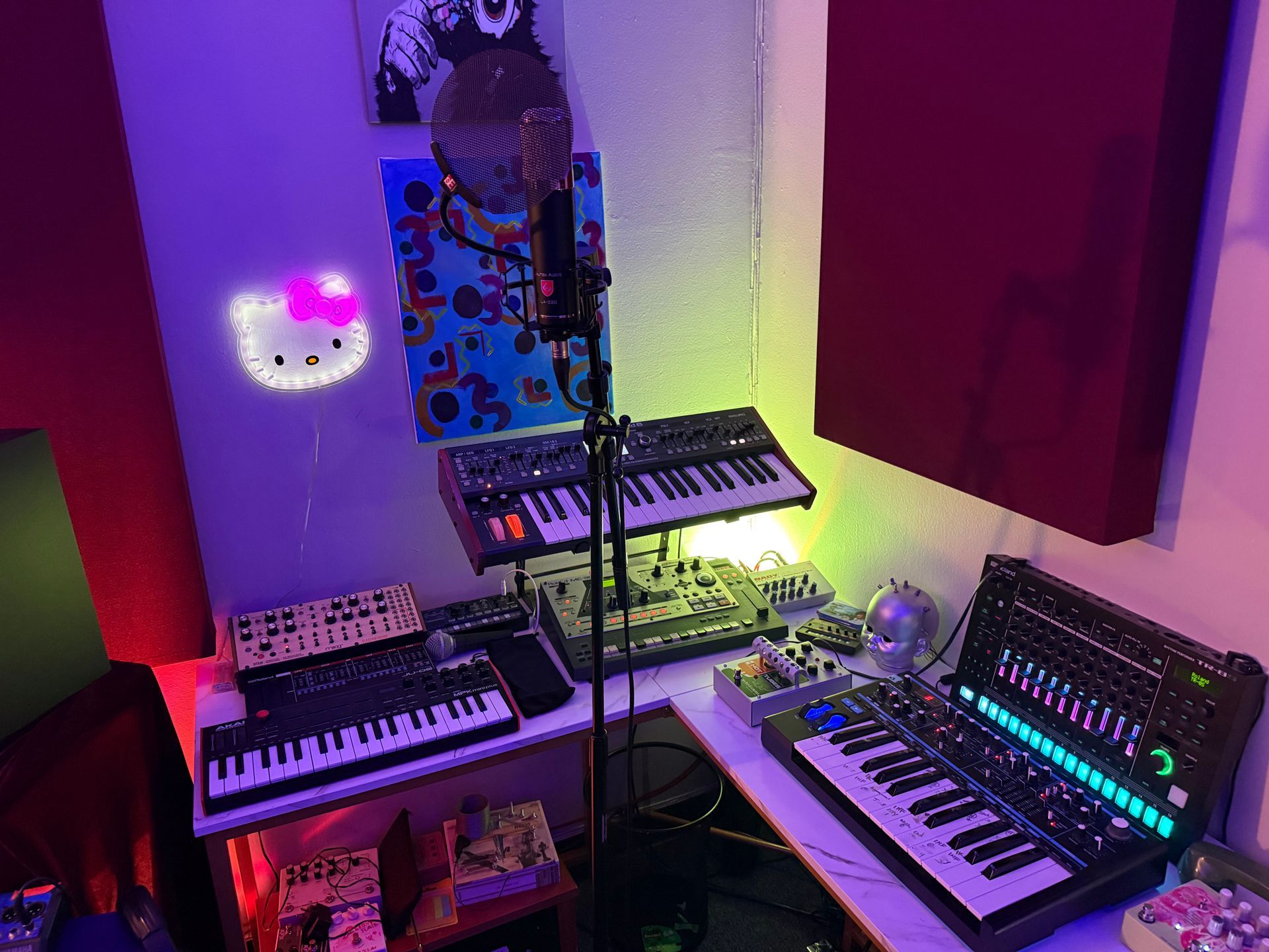 Compact music studio with two keyboards, mixer, and glowing purple-green LED lighting.