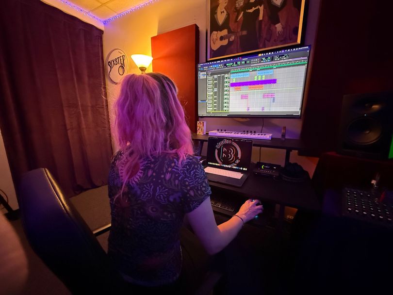 Person working at a desk with a computer in a dimly lit room, viewed from behind.