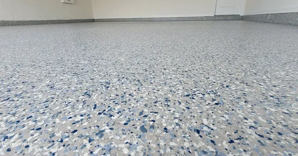 A garage floor with a speckled epoxy coating in blue, gray, and white.