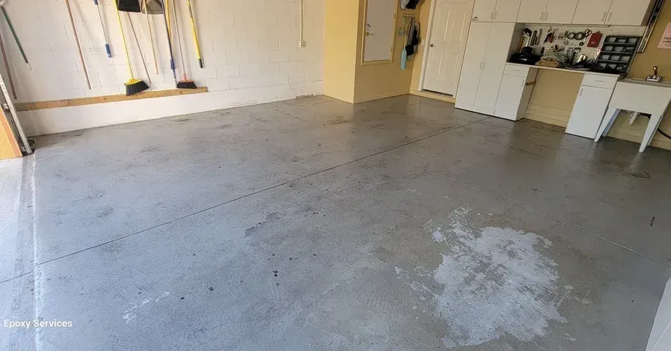 Garage interior with concrete floor, tools on the wall, and a washbasin.