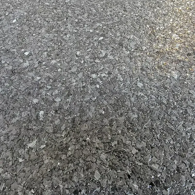 Close-up of a speckled, dark gray surface with tiny chips and flecks throughout.