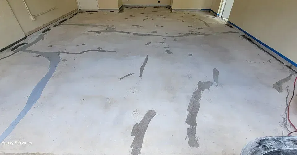 Concrete floor with cracks filled with gray sealant, prepped for flooring installation.