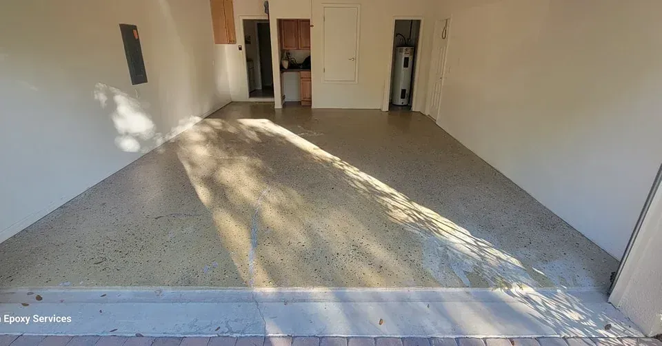 Empty garage interior with a concrete floor. Sunlight streams across the floor from the open garage door.