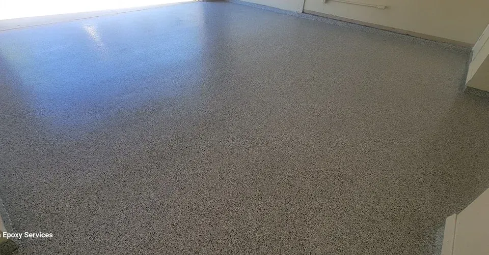 A light gray, speckled epoxy floor in a room, reflecting light.
