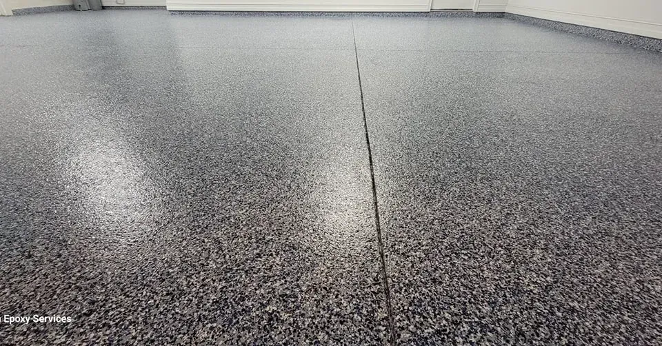 Gray epoxy-coated floor speckled with dark chips, bisected by a narrow seam.