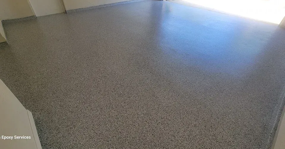 Polished gray concrete floor in a room, reflecting some light.