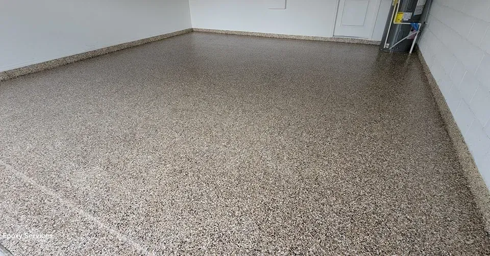 Garage floor with a speckled epoxy coating, reflecting the room's light.