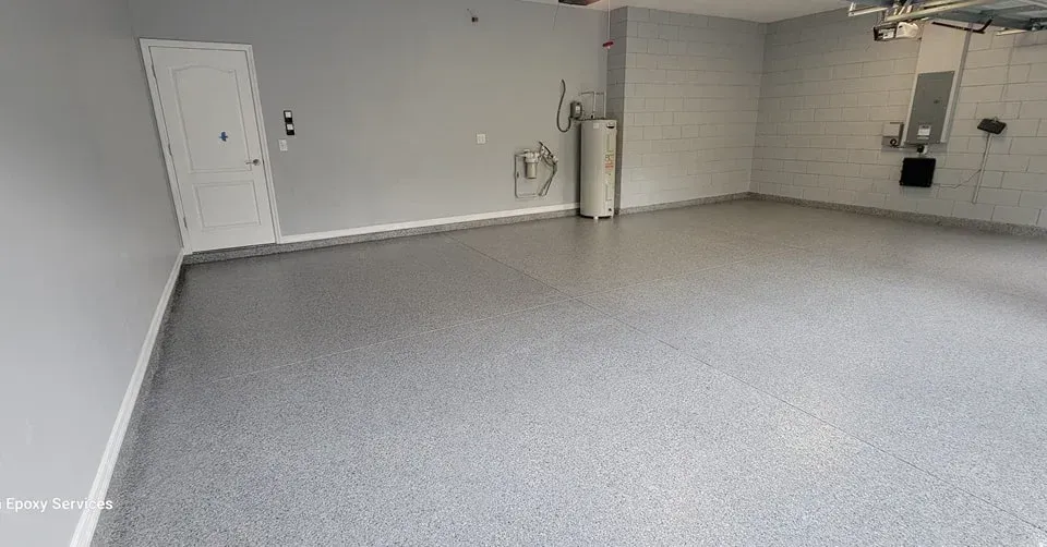 Empty gray garage with a shiny floor, water heater, and white door.