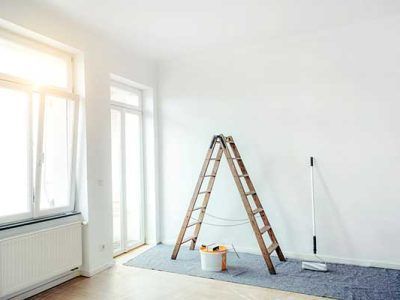 An empty room with a ladder and a mop in it.