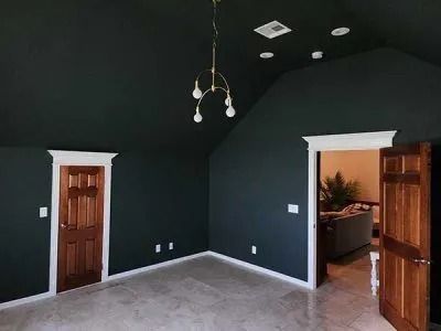 Empty room with dark walls, white trim, two wooden doors, and a hanging light fixture