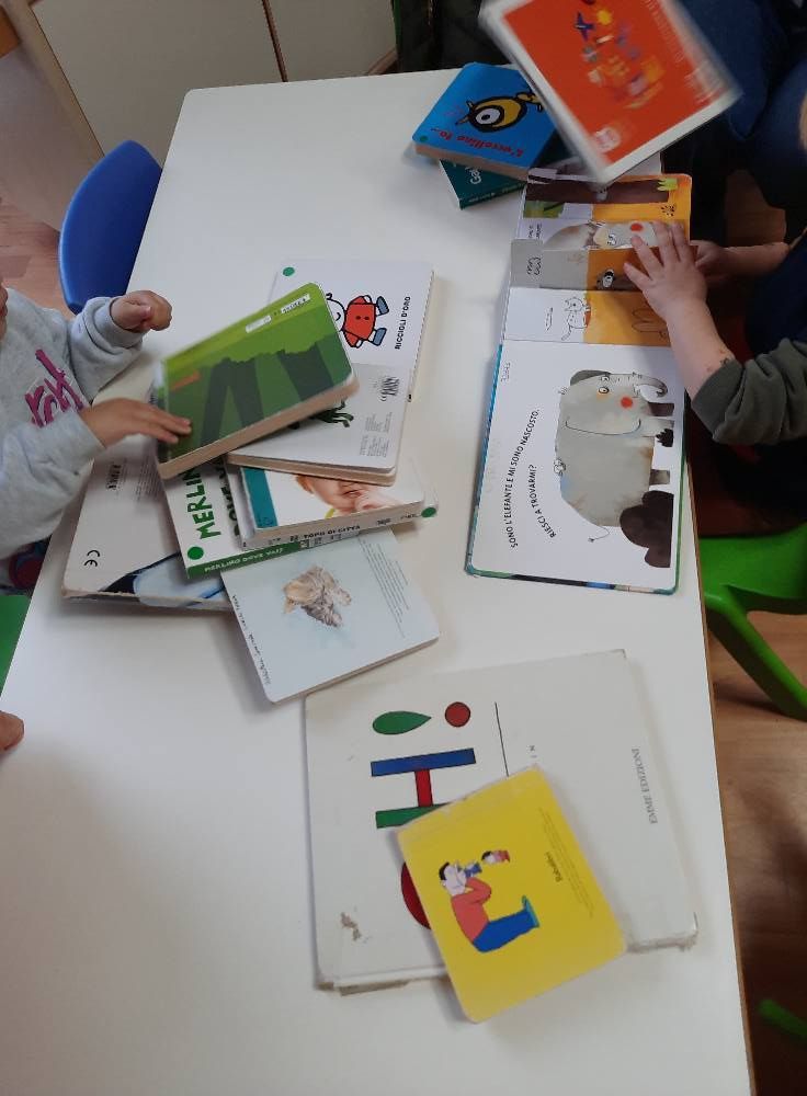 Libri per bambini e schede didattiche disposti su un tavolo durante un'attività di apprendimento.