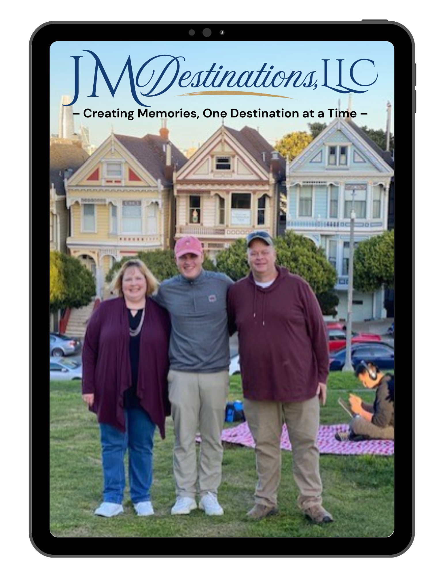 Three people standing outside in front of a house-shaped holiday display with a JM Destinations LLC sign.