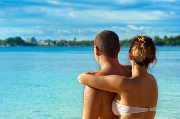 Two people embracing and looking out over a bright turquoise ocean