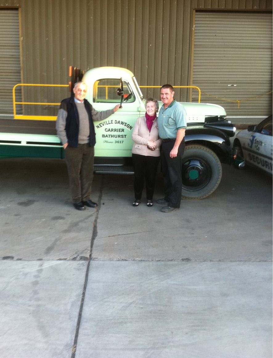 Man in Reflective Vest Smiles in Front of a Green Truck — Dawson's Removals In Kelso, NSW