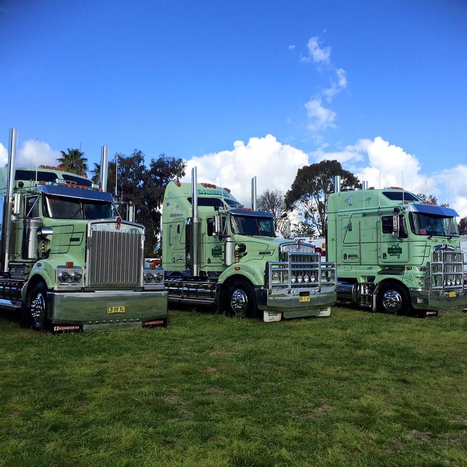 Three Green Semi-trucks Parked on Grass Under a Blue Sky — Dawson's Removals In Kelso, NSW