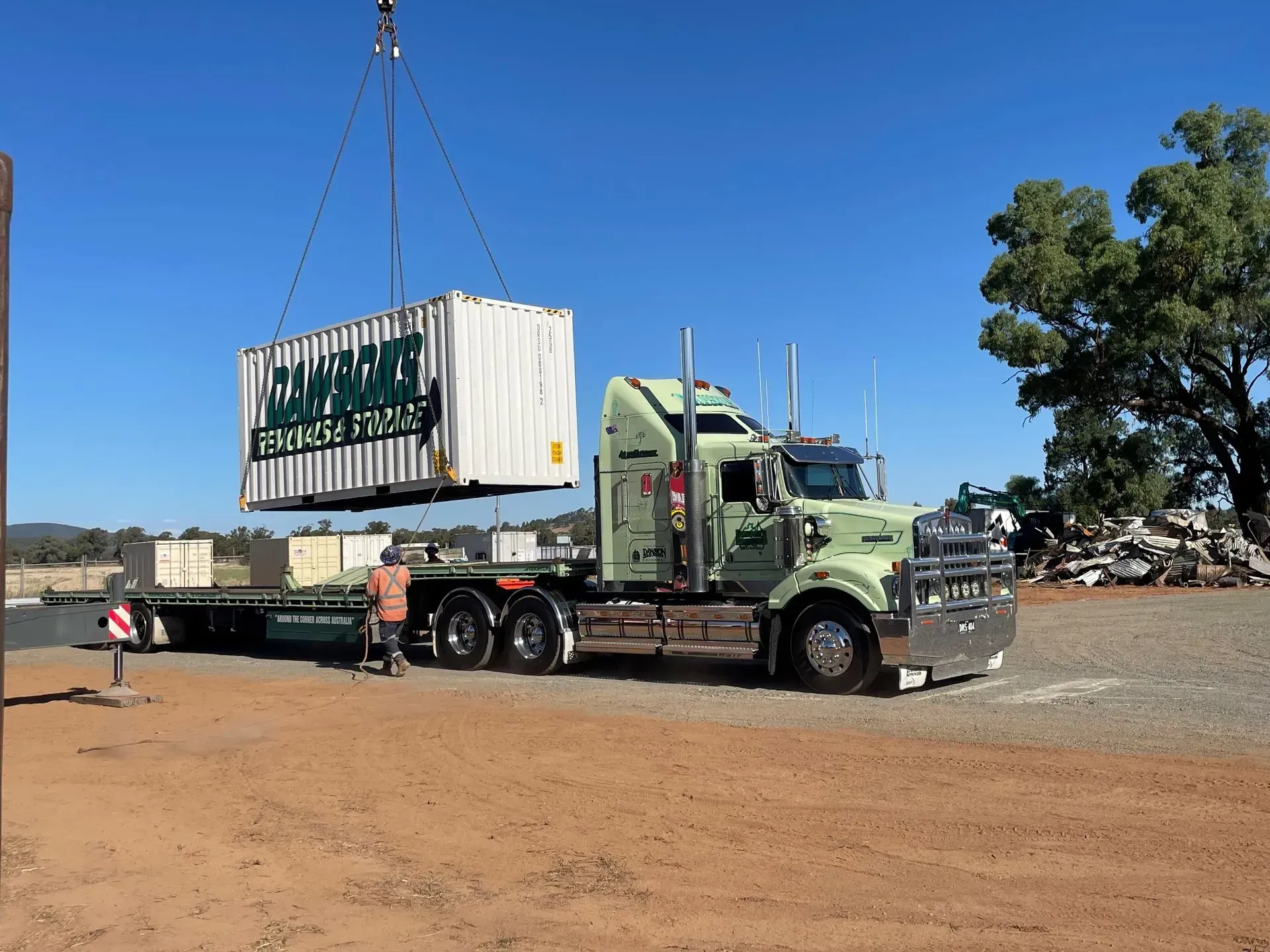 A large storage container is being lifted onto the back of a dawsons removals truck — Dawson's Removals In Dubbo, NSW