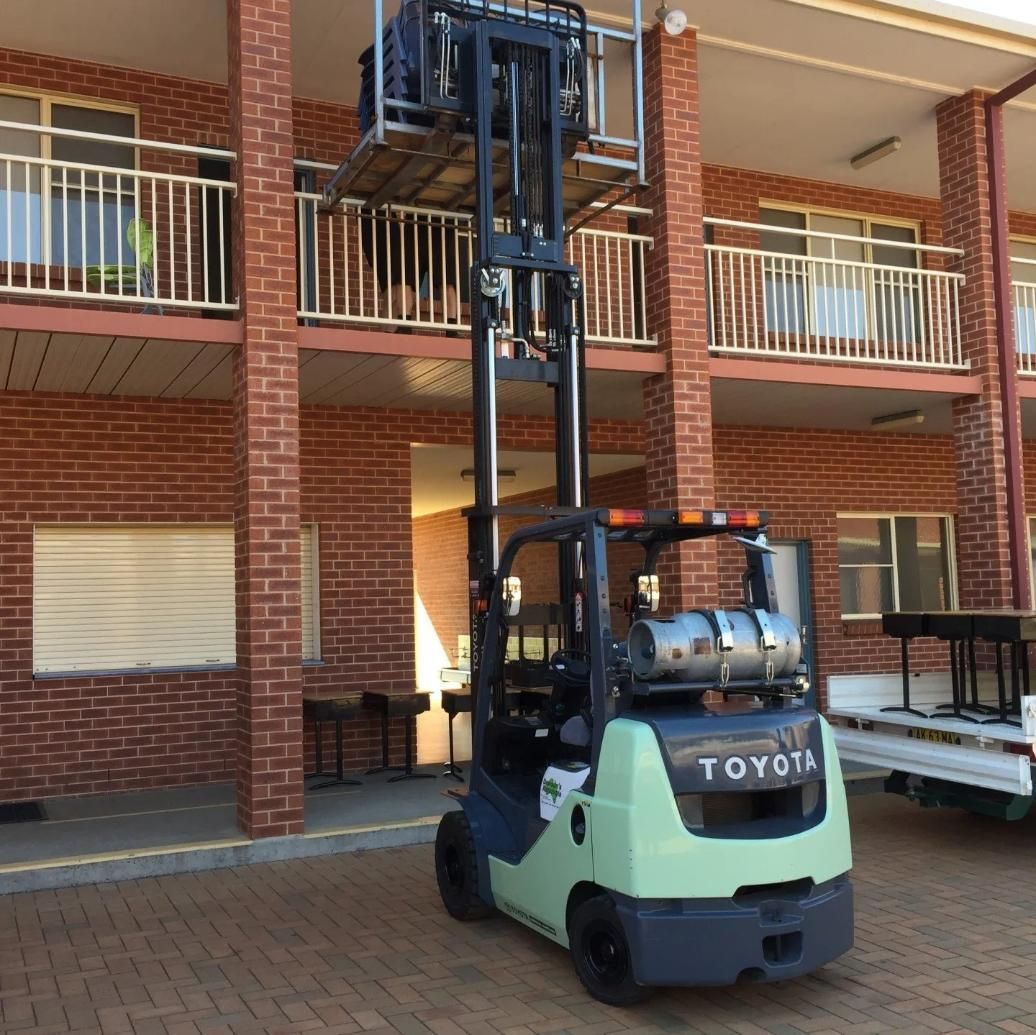 A Toyota Forklift With an Elevated Platform in Front of a Brick Building — Dawson's Removals In Kelso, NSW