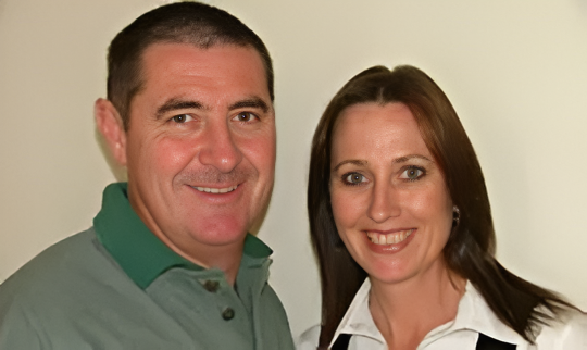 Man in Green Shirt and Woman in White Shirt Smiling, Posing Together — Dawson's Removals In Kelso, NSW