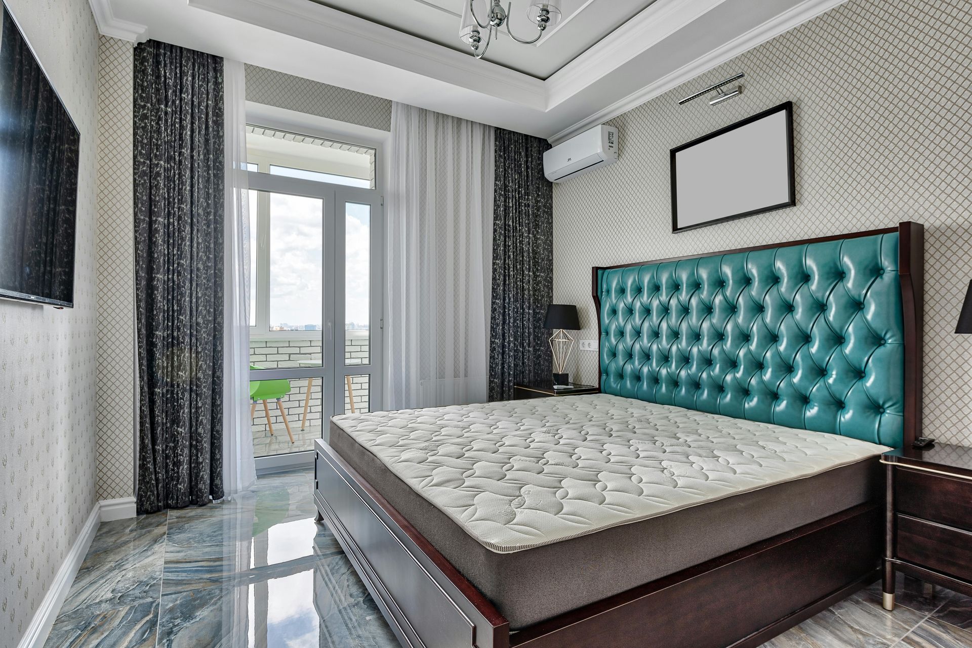 Bright modern bedroom with teal tufted headboard, large bed, curtains, and balcony doors.